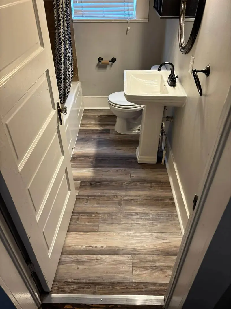 Small bathroom with new wood-look plank flooring, white baseboard and a pedestal sink