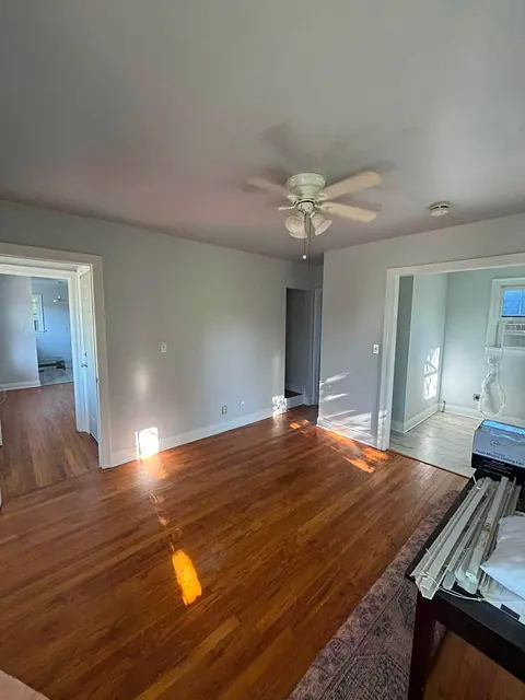 Bright living room with hardwood floors, gray walls and white trim after renovation