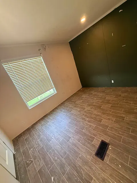 Room with a newly laid wood-look plank tile floor and a dark green accent wall