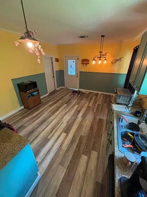 Finished wood-look plank floor in a kitchen with yellow walls and teal wainscoting