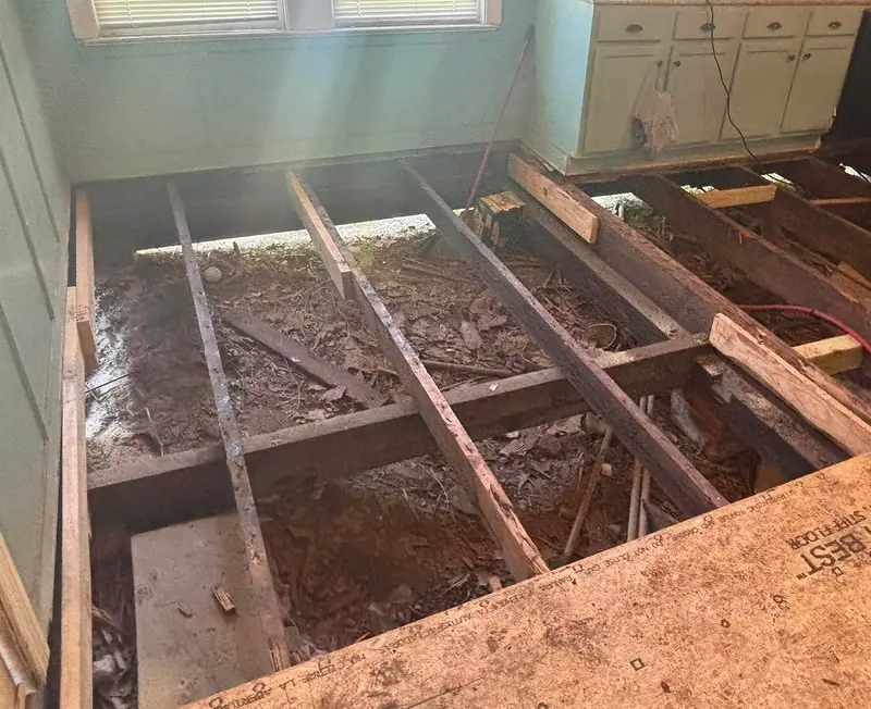 Kitchen floor opened up to the joists with new lumber and a subfloor panel being fitted