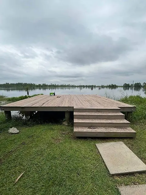 Weathered wooden deck and steps at the edge of a lake before re-decking