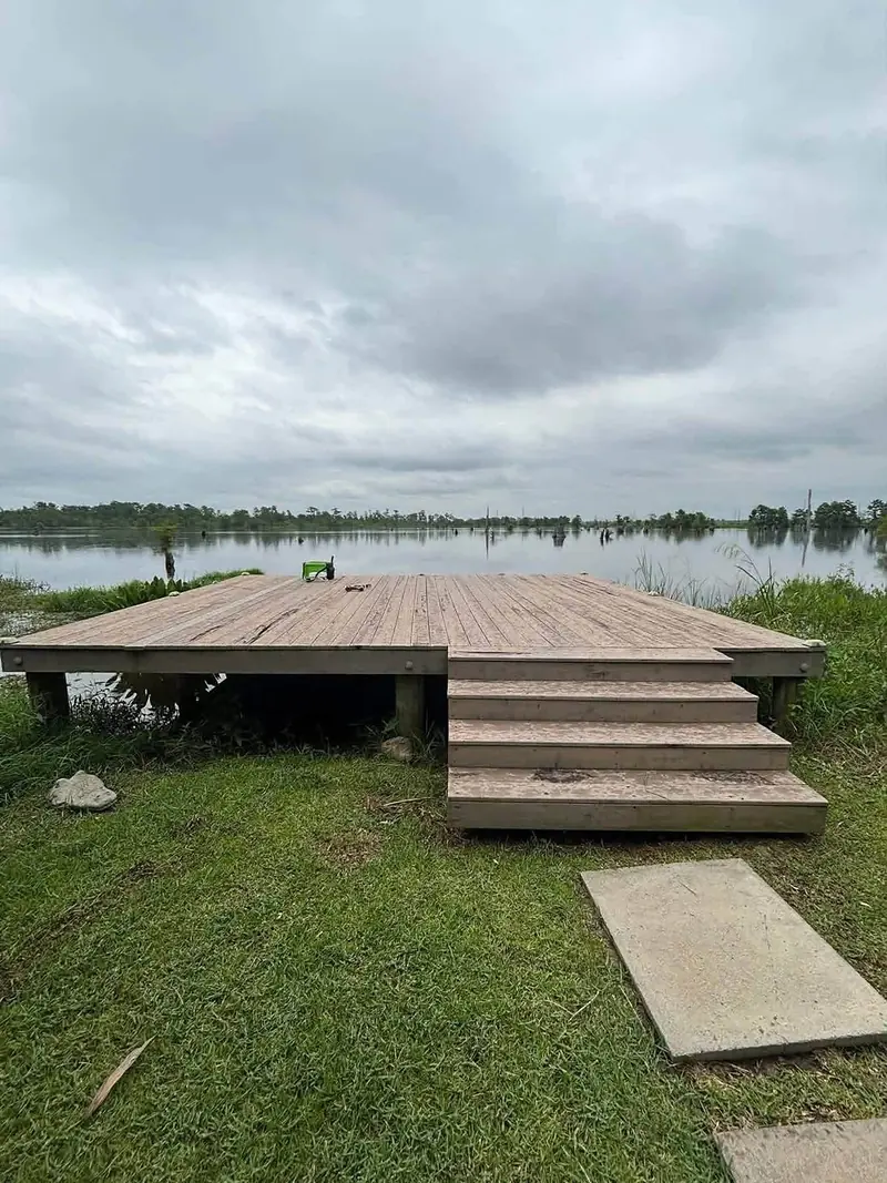 Weathered wooden deck and steps at the edge of a lake before re-decking
