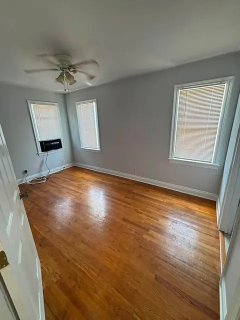 Bedroom with hardwood floor, gray walls and white window trim