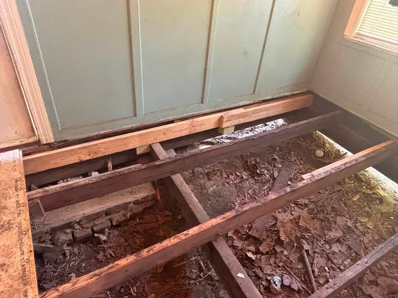 Exposed floor joists beside a paneled wall with new lumber fastened alongside