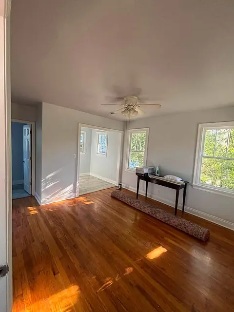 Sunlit living room with hardwood floors and cased openings