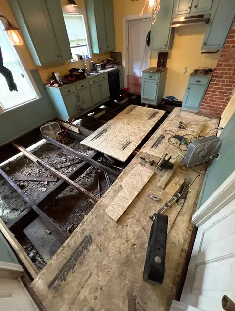 Kitchen floor removed to expose the joists, with new subfloor panels being laid