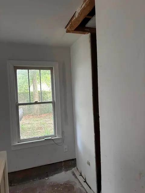 Wall opened beside a window with the framing header exposed