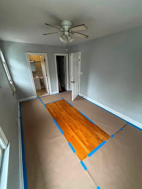 Bedroom floor covered with protective paper and blue tape during renovation
