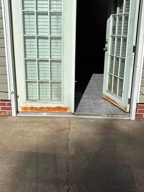 Exterior French doors with rusted lower edges before threshold repair