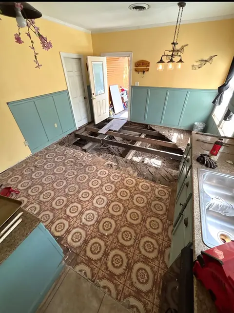 Kitchen with an old patterned vinyl floor and a section opened to the joists