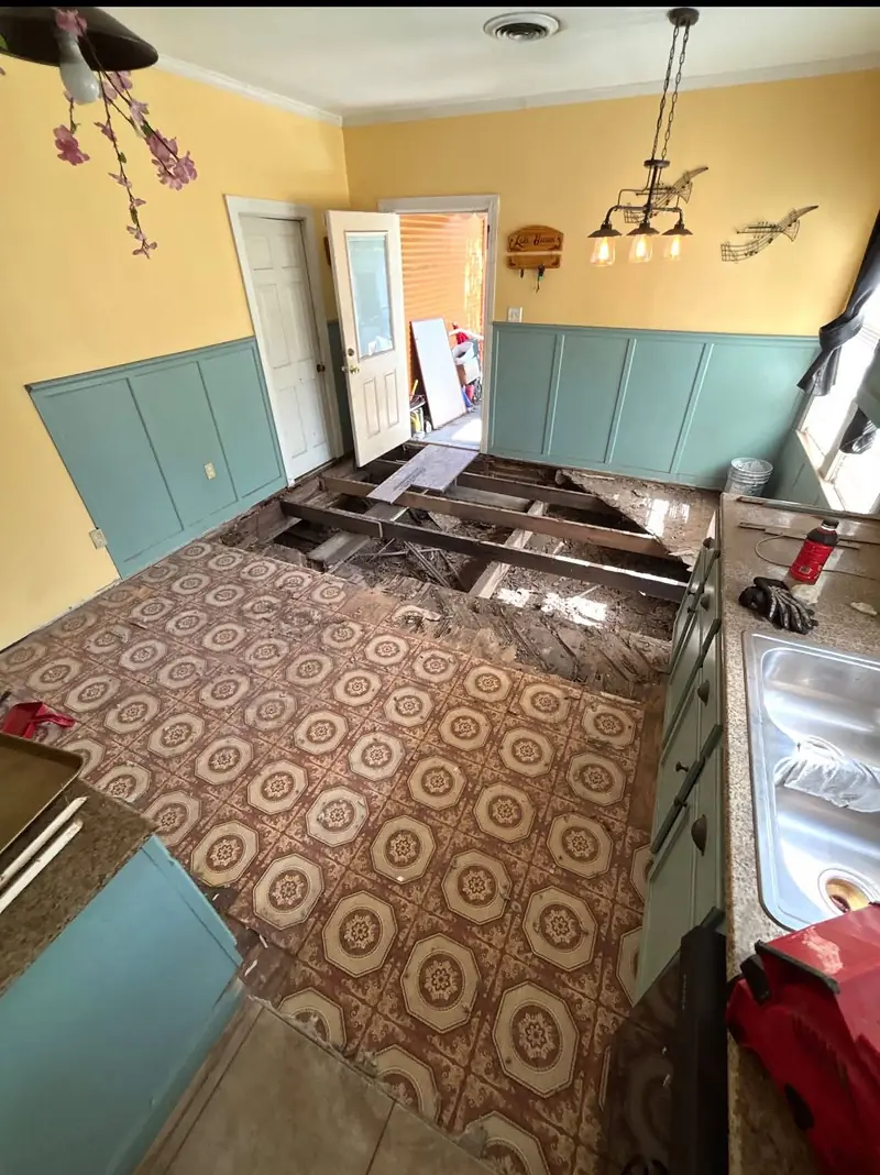 Kitchen with an old patterned vinyl floor and a section opened to the joists