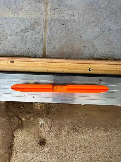 Level resting on a newly installed door sill above a concrete slab